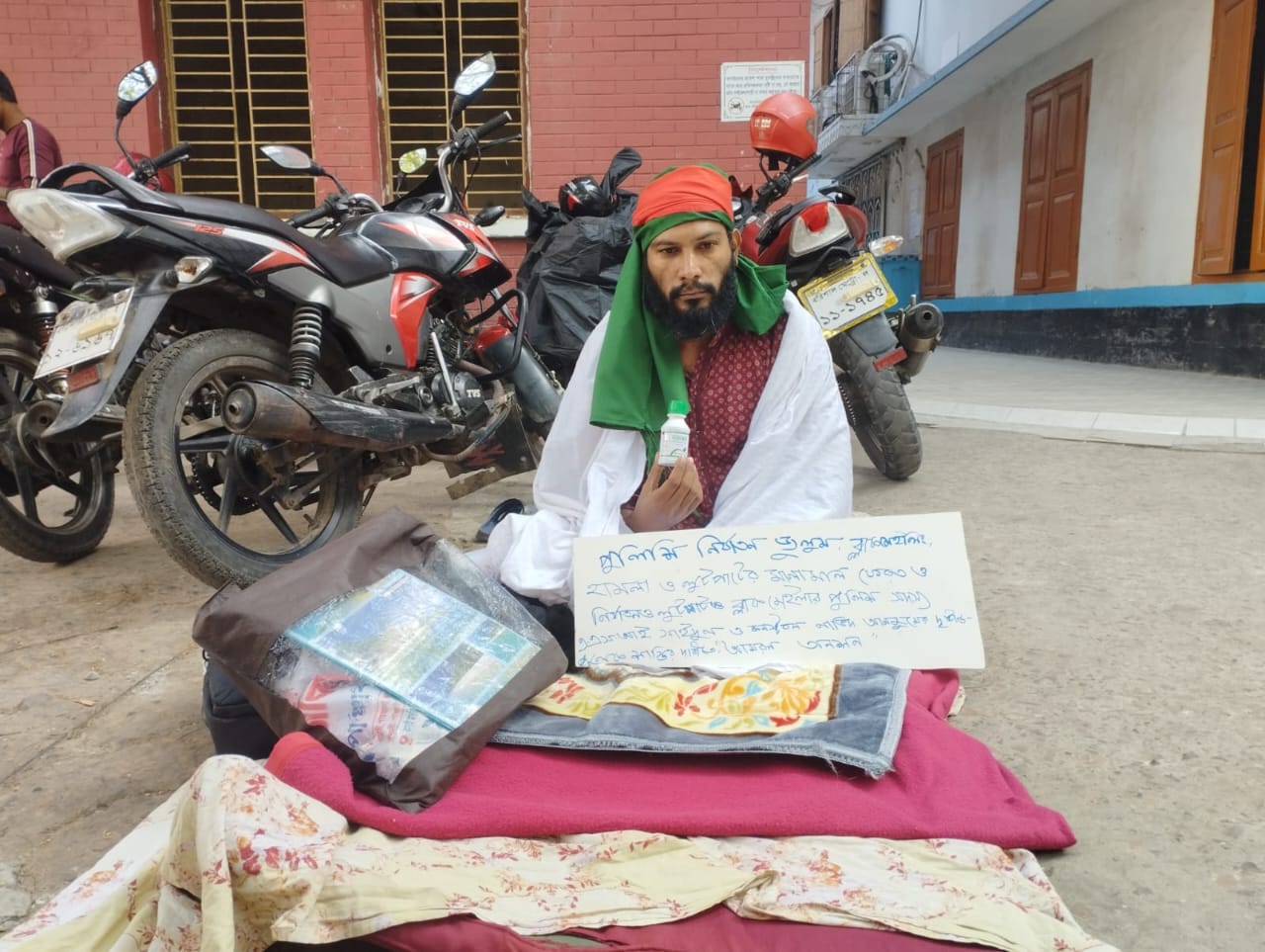 শরীরে কাফনের কাপড় জড়িয়ে বিষের বোতল নিয়ে সাংবাদিকের অবস্থান